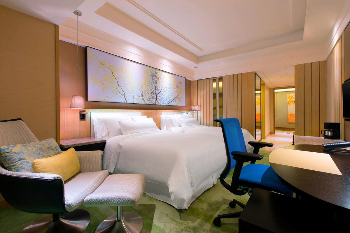 Une chambre d’hôtel avec un grand lit, un bureau, une chaise, un canapé et un tableau au mur.