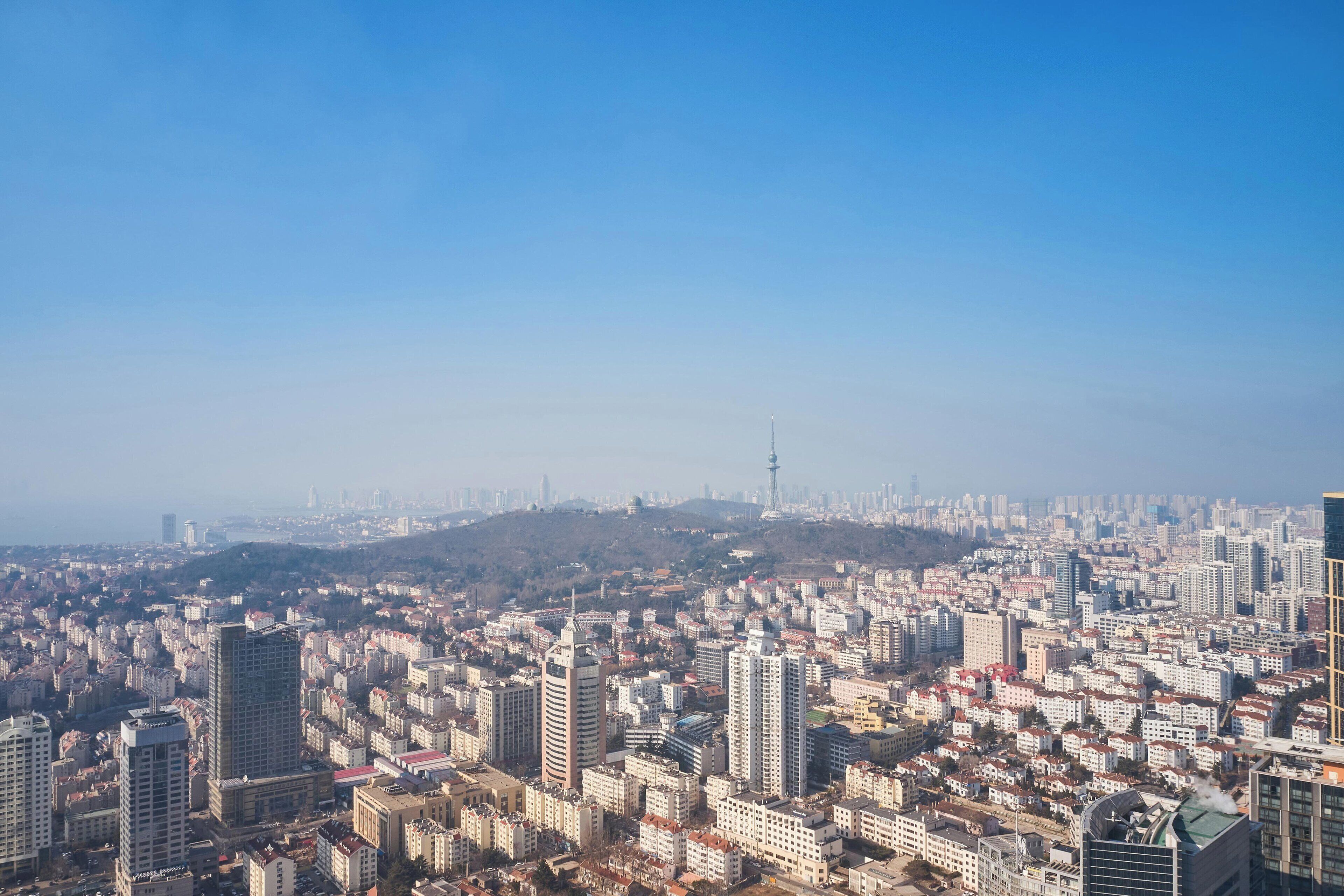 Un paisaje urbano con numerosos edificios altos y una torre destacada a lo lejos.