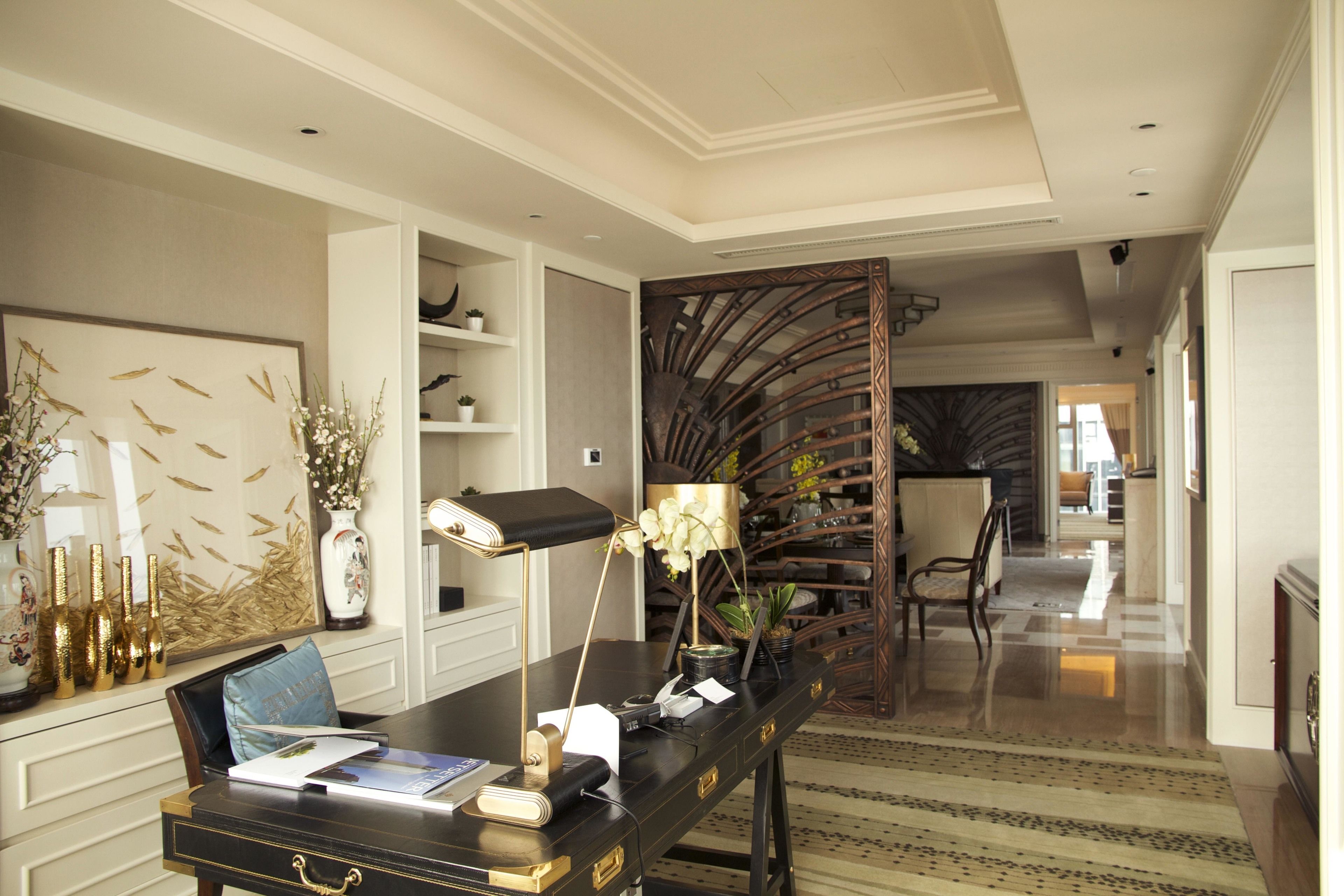 Una habitación luminosa y elegante con escritorio, libros, lámpara y una planta decorativa.