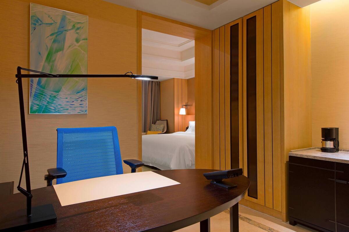 Une chambre d’hôtel équipée d’un bureau, d’une chaise, d’un lit et d’une machine à café.