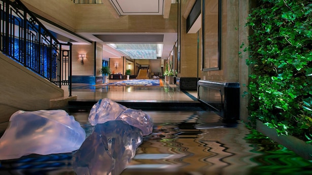 A modern hotel lobby with a central staircase, a reception area, and a decorative ice sculpture. - The Westin Qingdao (Qingdao)
