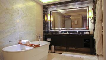 A modern bathroom with a freestanding bathtub, a large mirror, and a dark marble countertop.