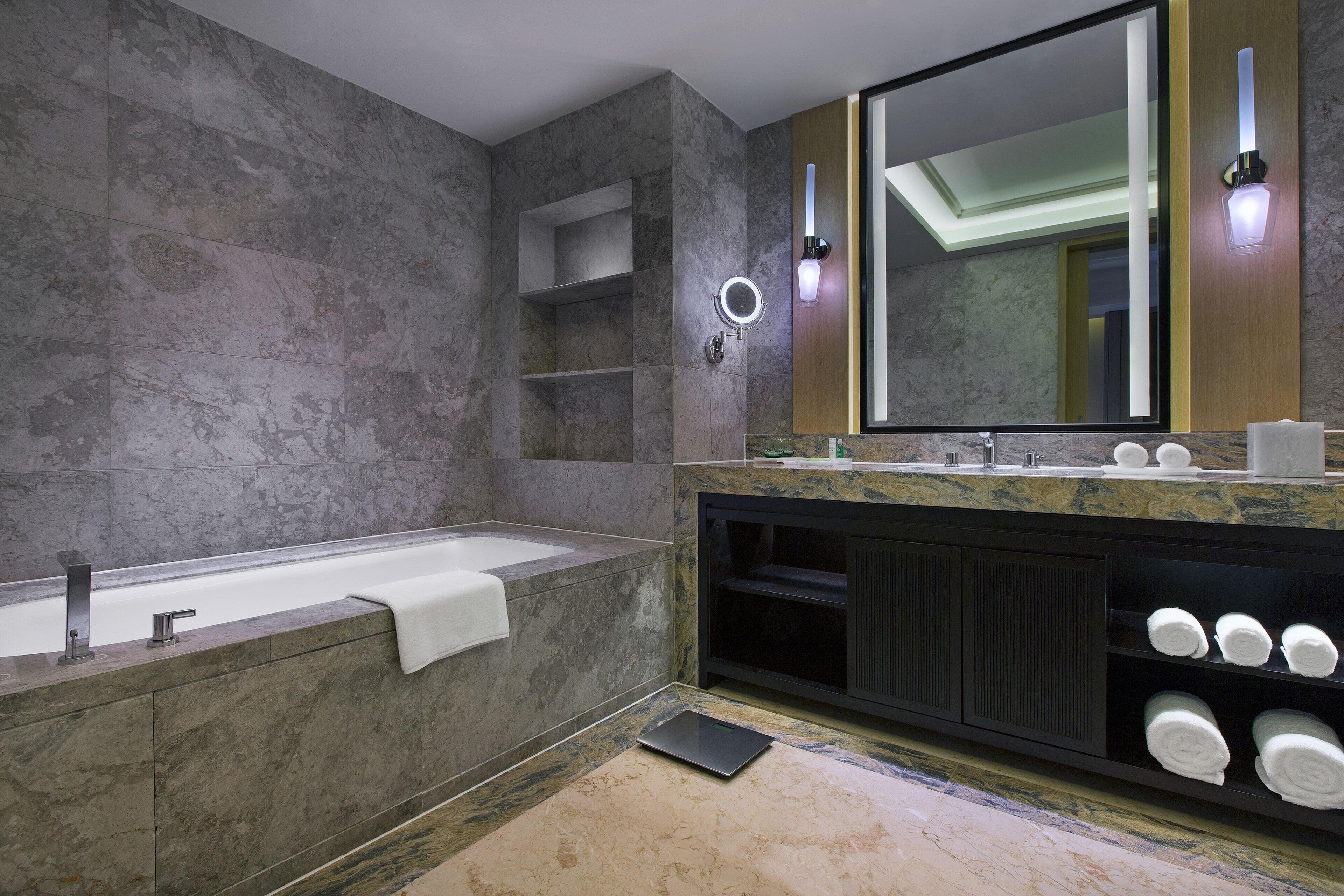 A modern bathroom with a freestanding bathtub, a large mirror, and built-in shelves.