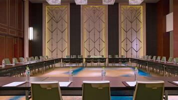A conference room with a long table, chairs, water bottles, and a chandelier.