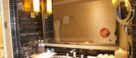 A bathroom with a marble sink, a large mirror, and a towel rack.