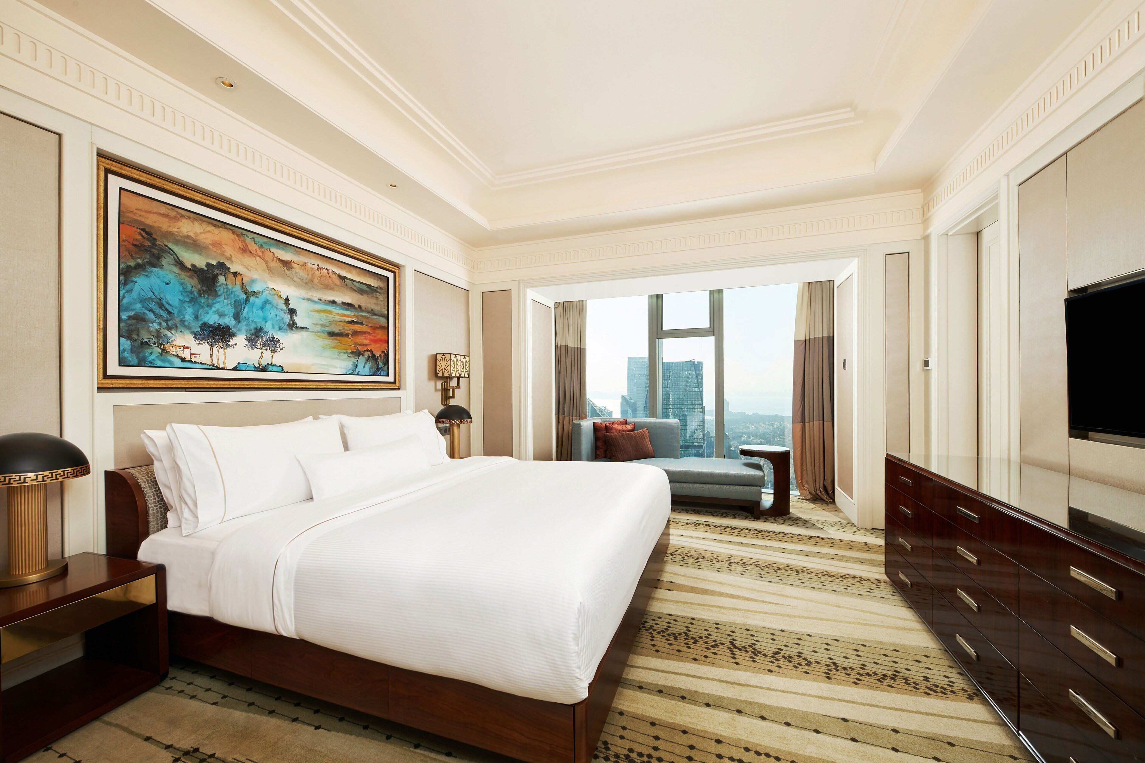 Una habitación de hotel amplia con una cama grande, vistas a la ciudad, un televisor de pantalla plana y una decoración moderna.