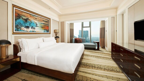Una habitación de hotel amplia con una cama grande, vistas a la ciudad, un televisor de pantalla plana y una decoración moderna.