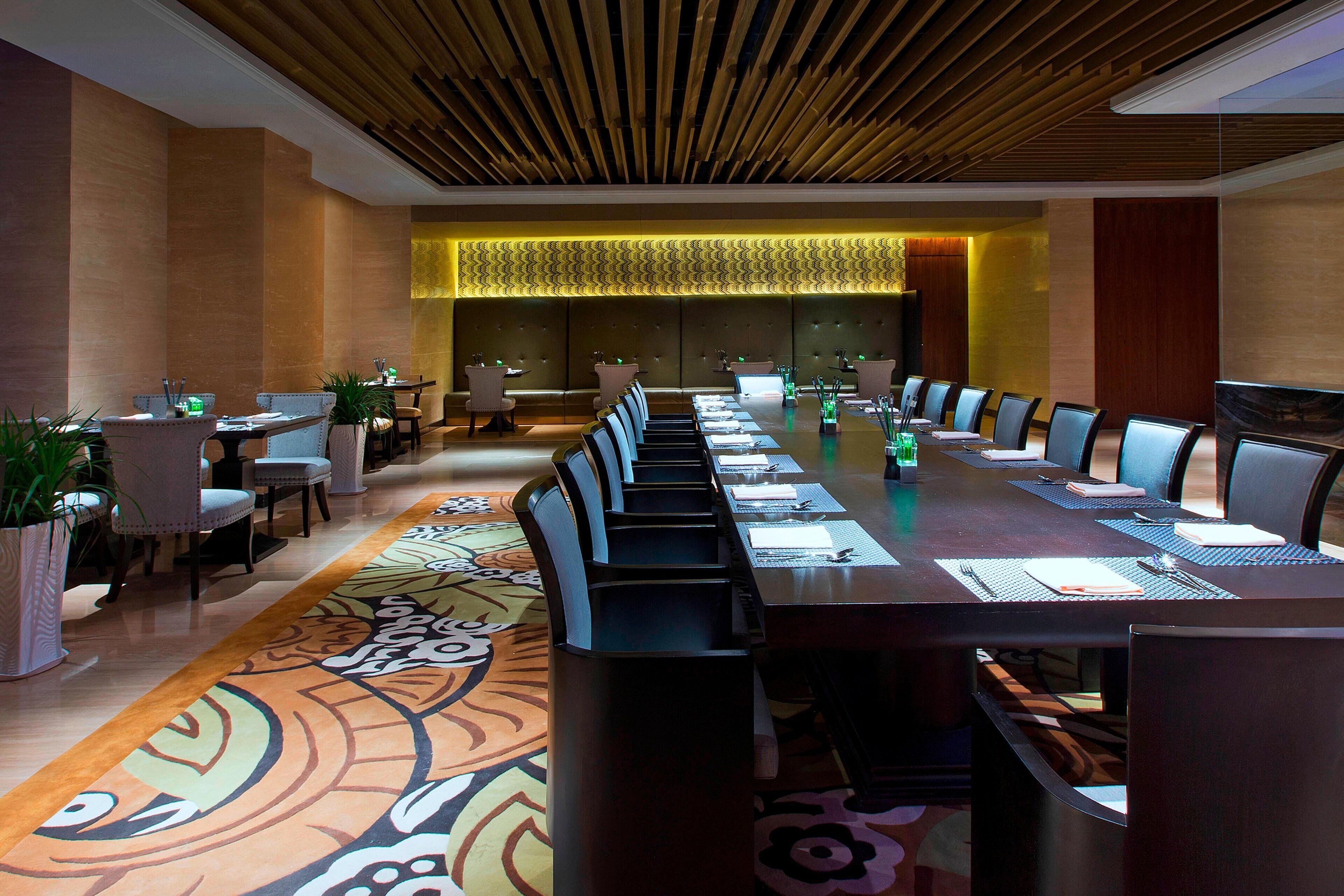 A conference room with a long table, chairs, and a patterned carpet.
