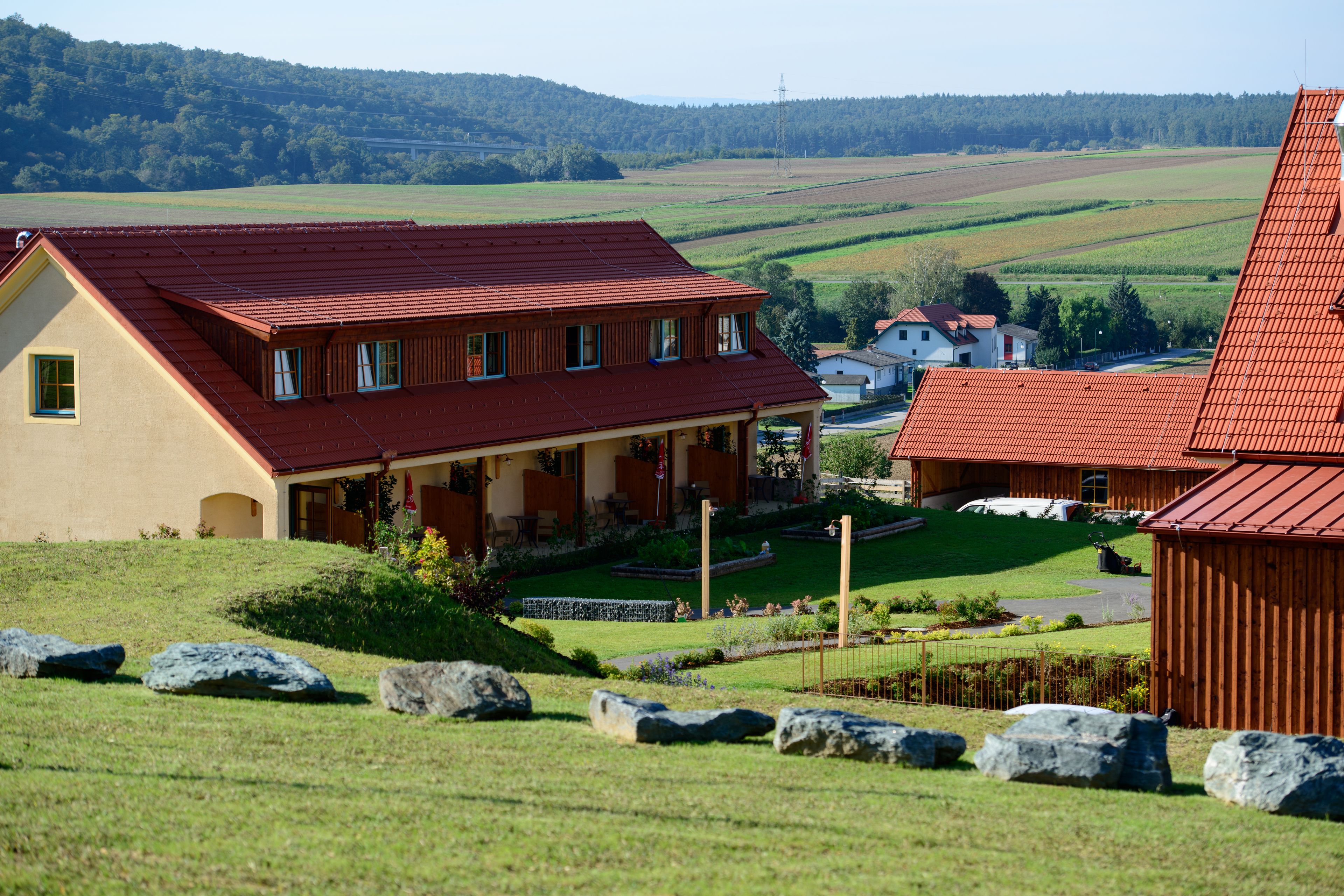 A house with a red roof, a porch, and a garden with rocks and plants.