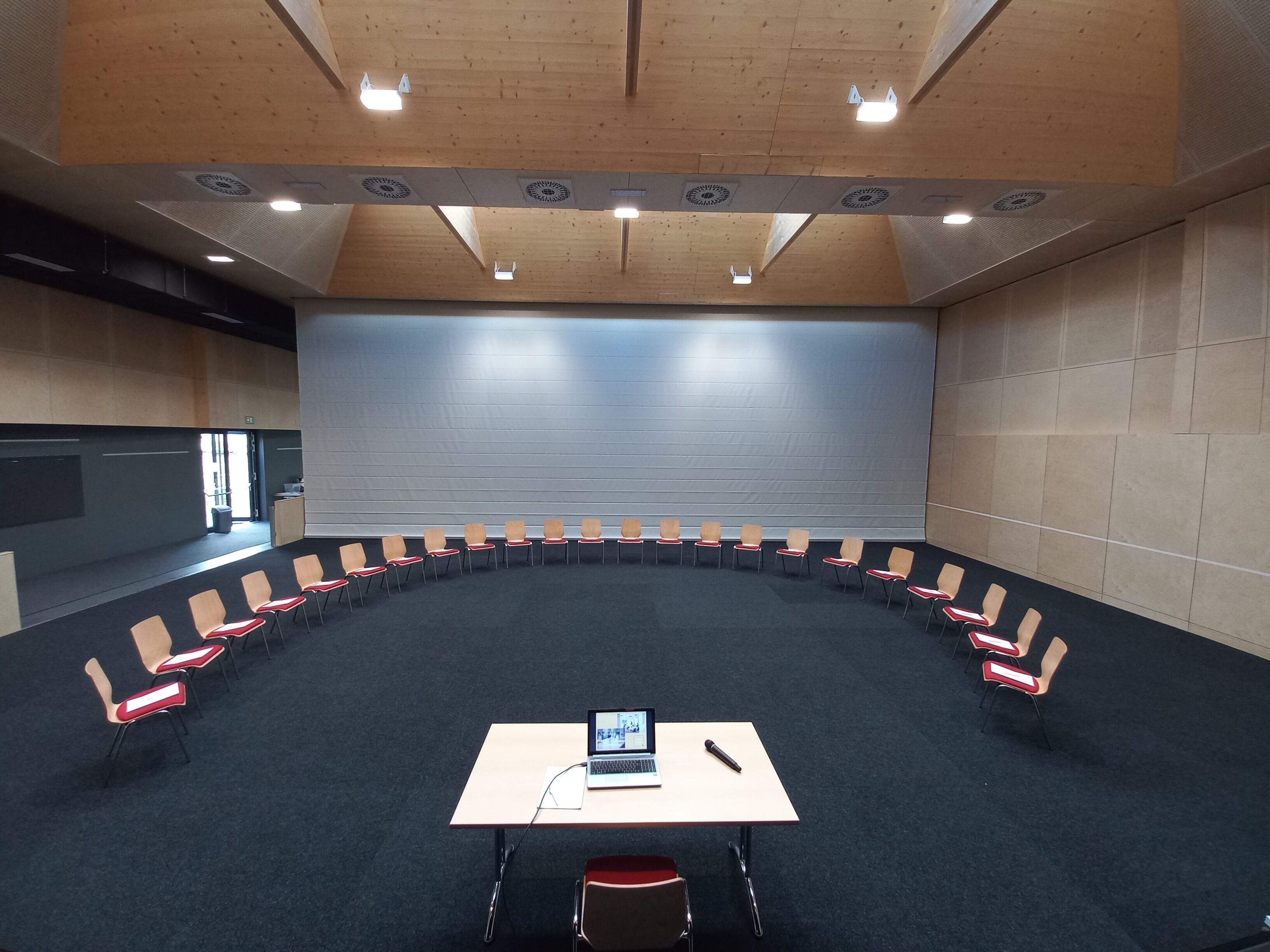 Un salón de conferencias con una mesa larga, sillas y un ordenador portátil.