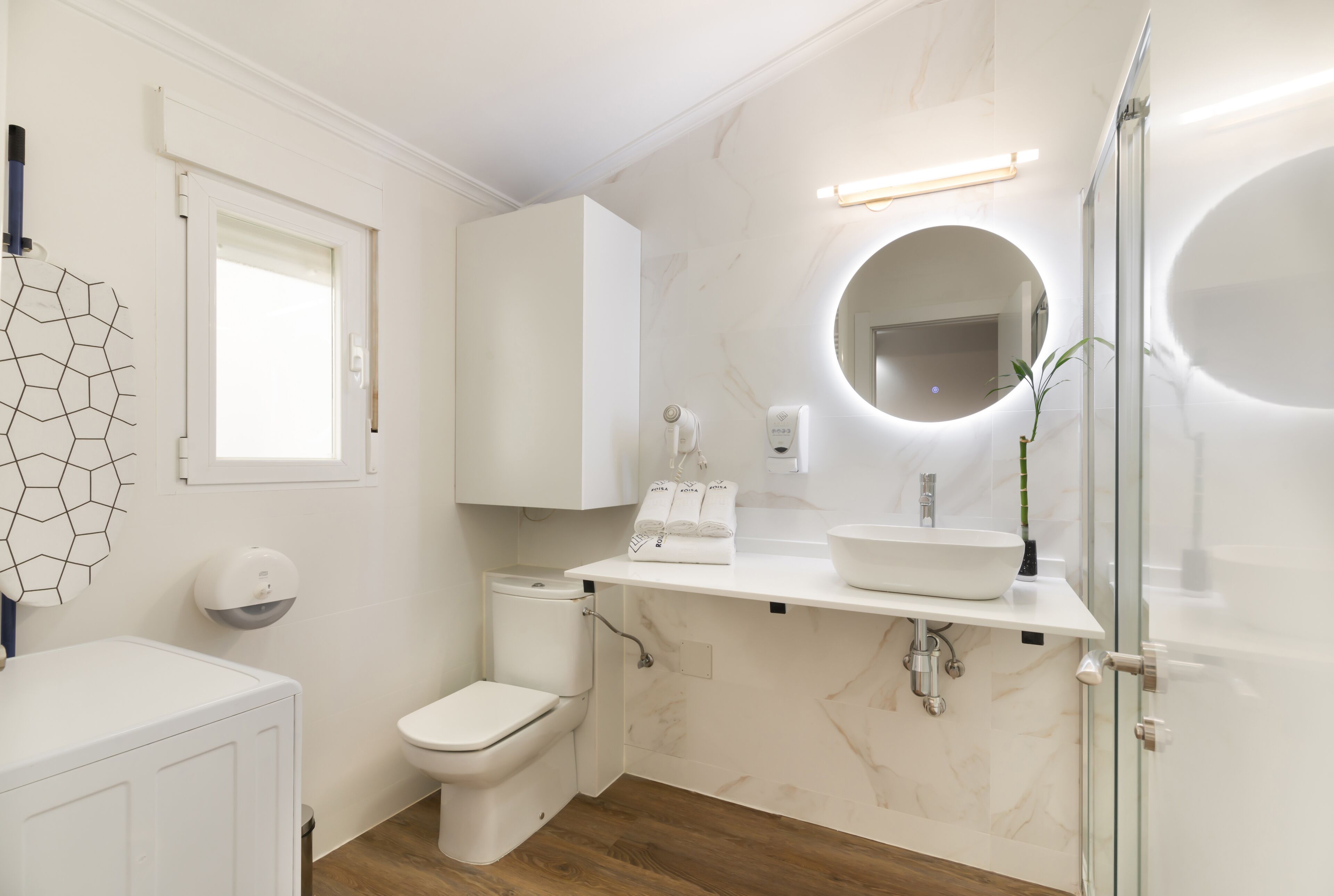 Et moderne badeværelse med toilet, vask og bruser.