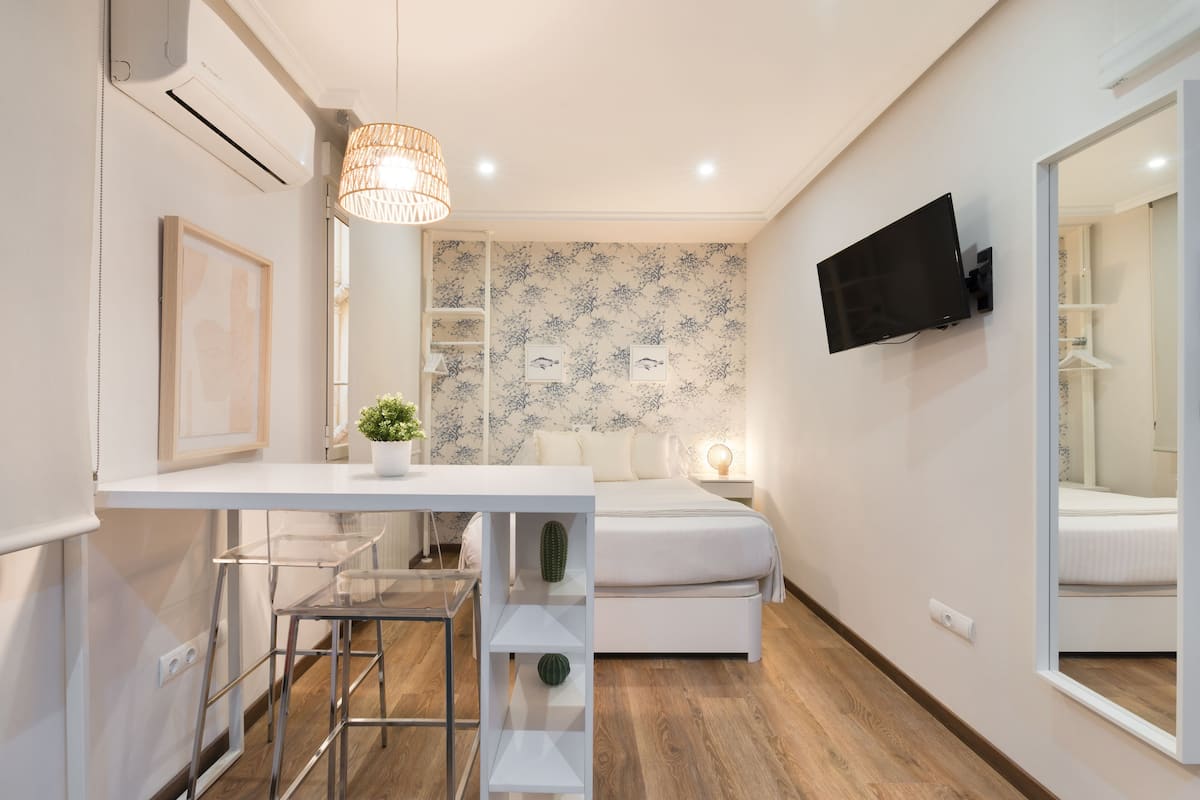 A modern bedroom with a bed, bedside table, and a mounted TV.