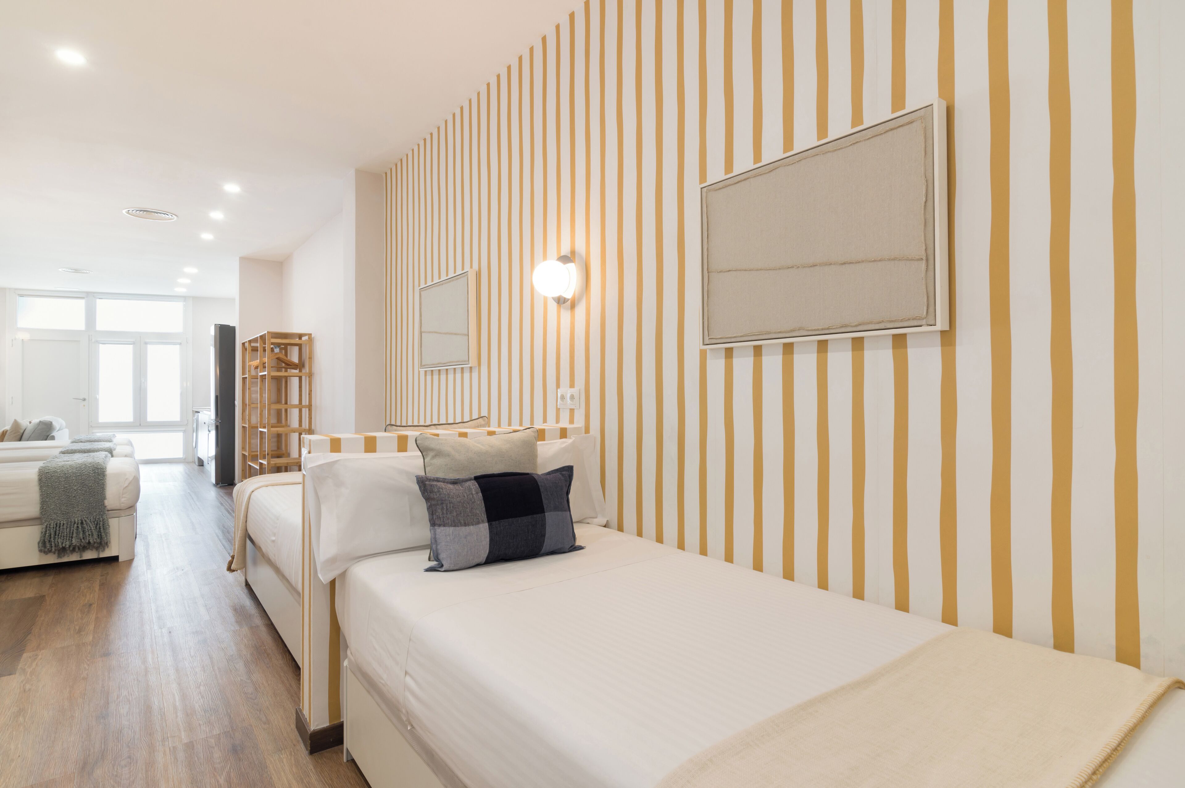 Ein Hotelzimmer mit einem Bett, einem Nachttisch, einem Spiegel und einer Wand mit vertikalen Streifen.