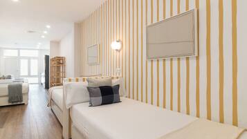 Ein Hotelzimmer mit einem Bett, einem Nachttisch, einem Spiegel und einer Wand mit vertikalen Streifen.