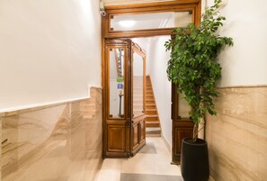 A hallway with a wooden door, a potted plant, and a staircase.