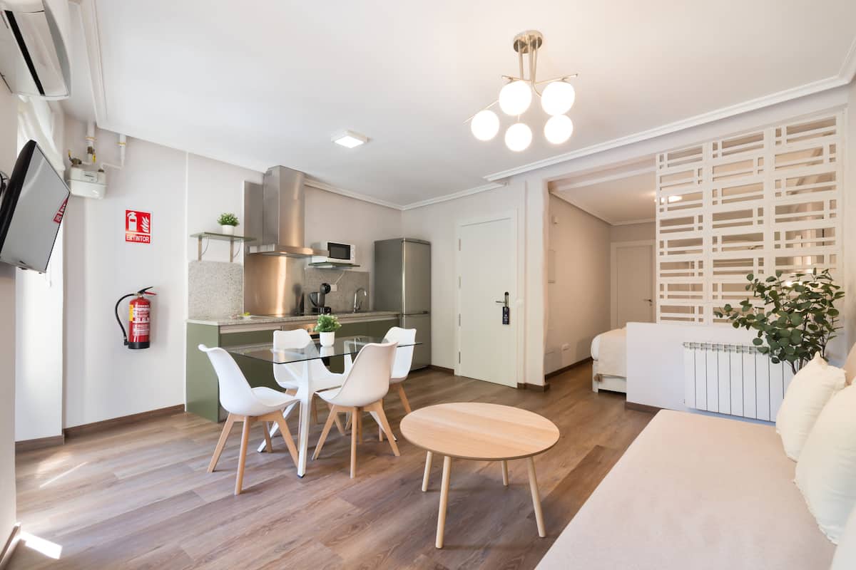 A modern kitchen with a dining area, a living room, and a white sofa.