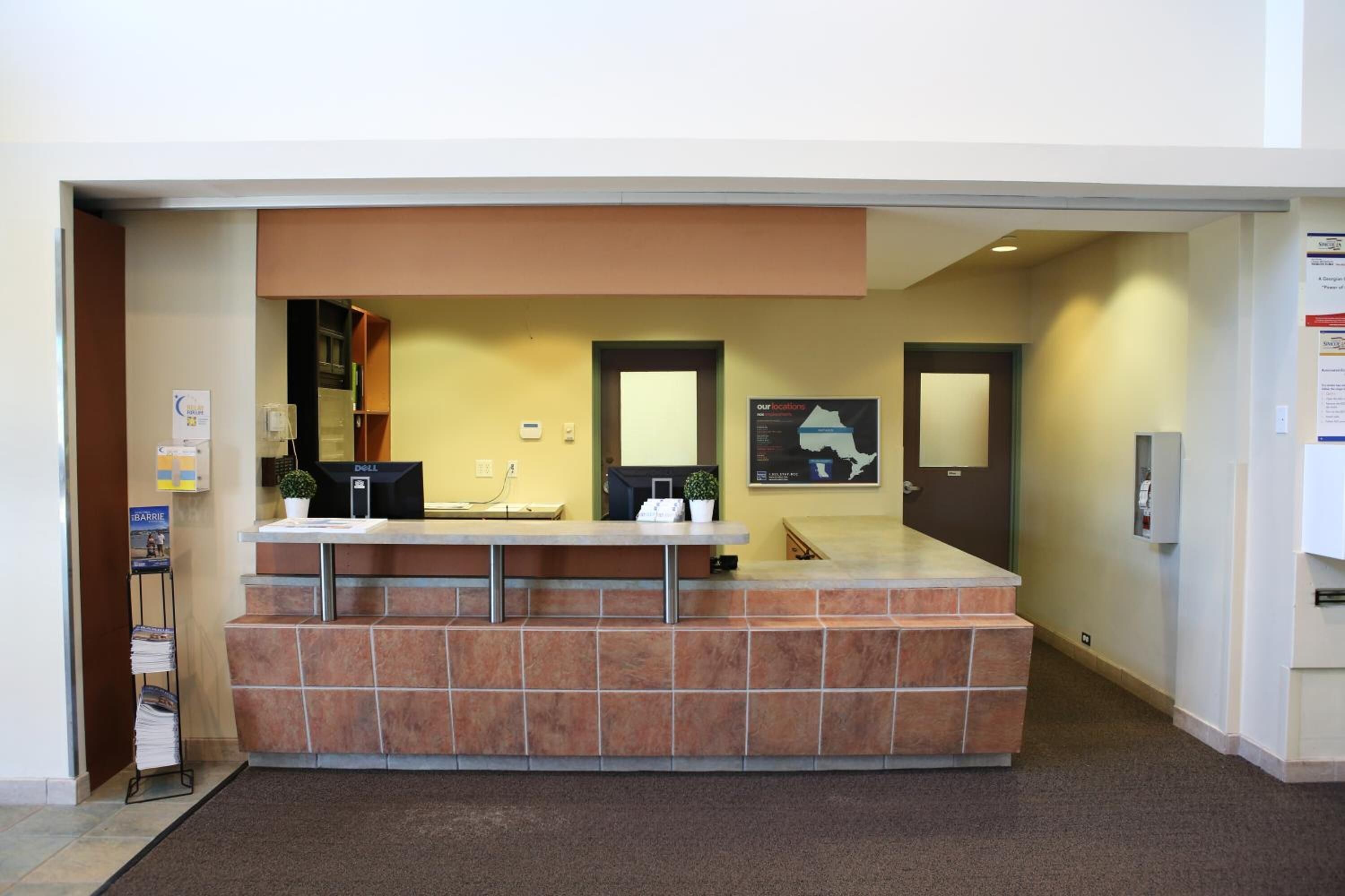 A reception desk with a computer, a plant, and a map on the wall.