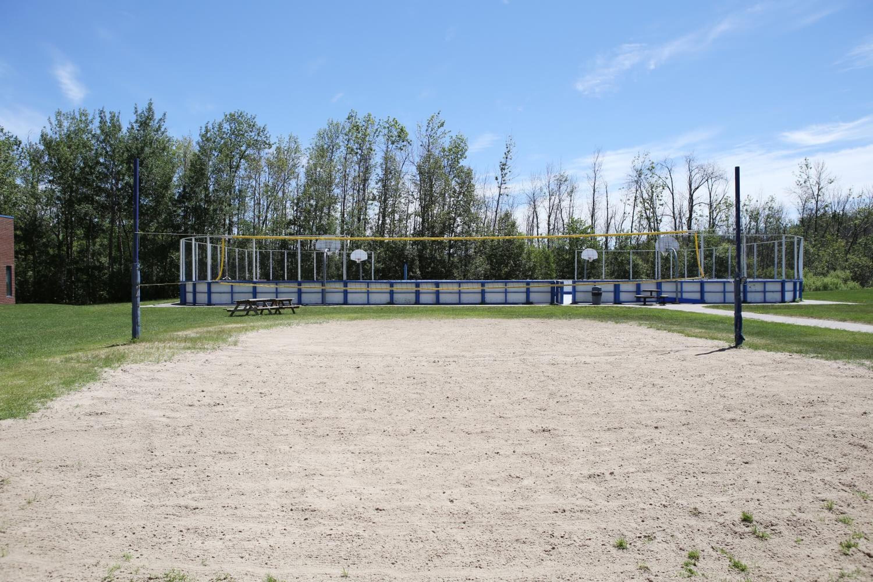 Ein Baseballfeld mit einem Kiesplatz, einer Holzbank und einem blau-gelben Zaun.