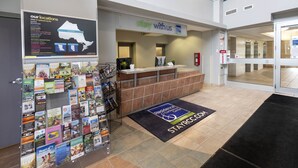 Zona de recepción de hotel con un mapa de ubicaciones, un letrero que dice 'Quédate con nosotros' y un tapete con la inscripción 'Corazón de Canadá'.