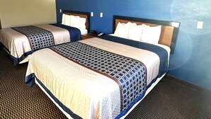 A hotel room with two beds, a blue accent wall, and a patterned carpet. - Eco-Lux Inn (Norfolk)