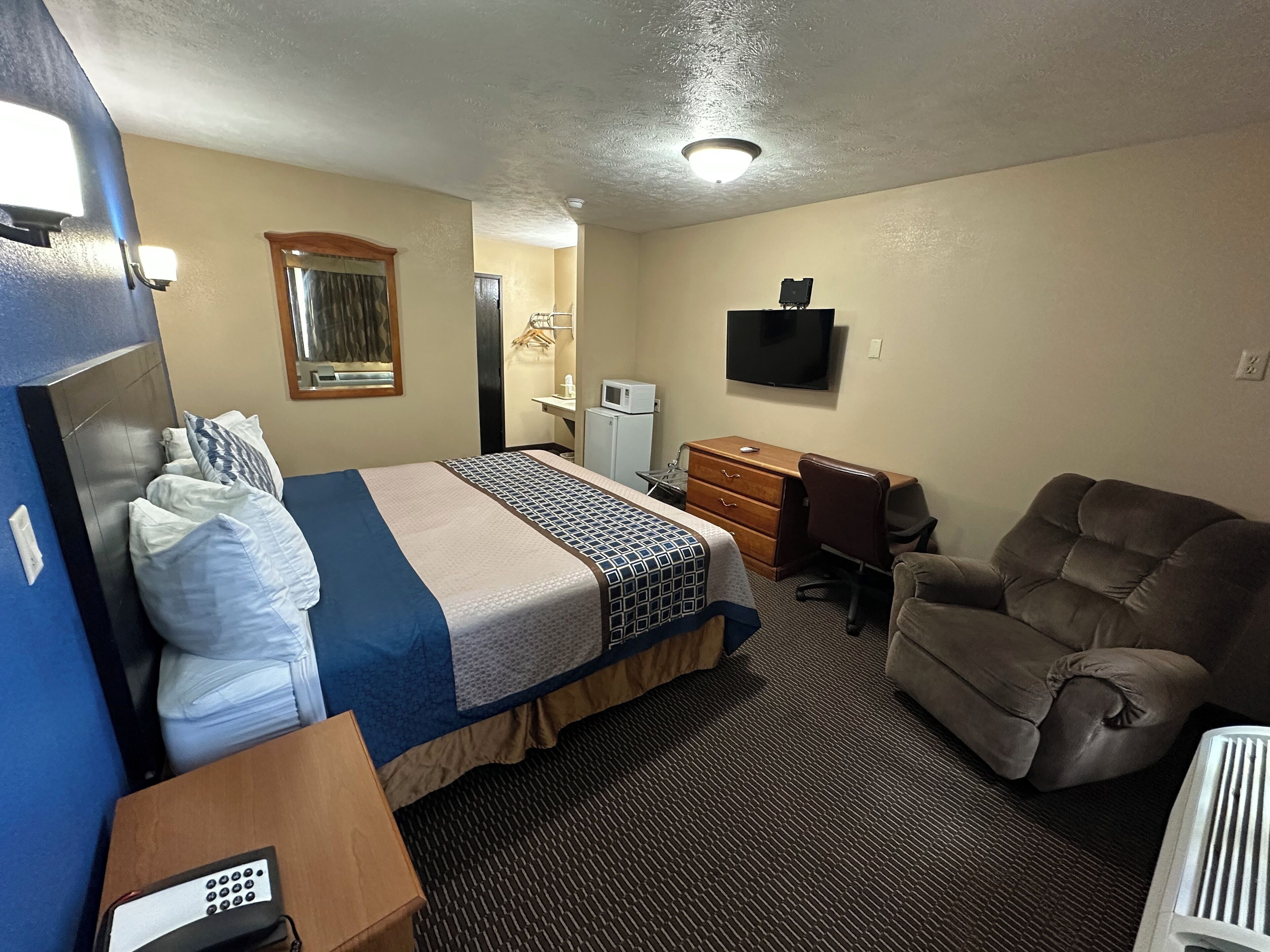 Une chambre d’hôtel équipée d’un lit, d’un bureau, d’une chaise, d’une télévision et d’une kitchenette.