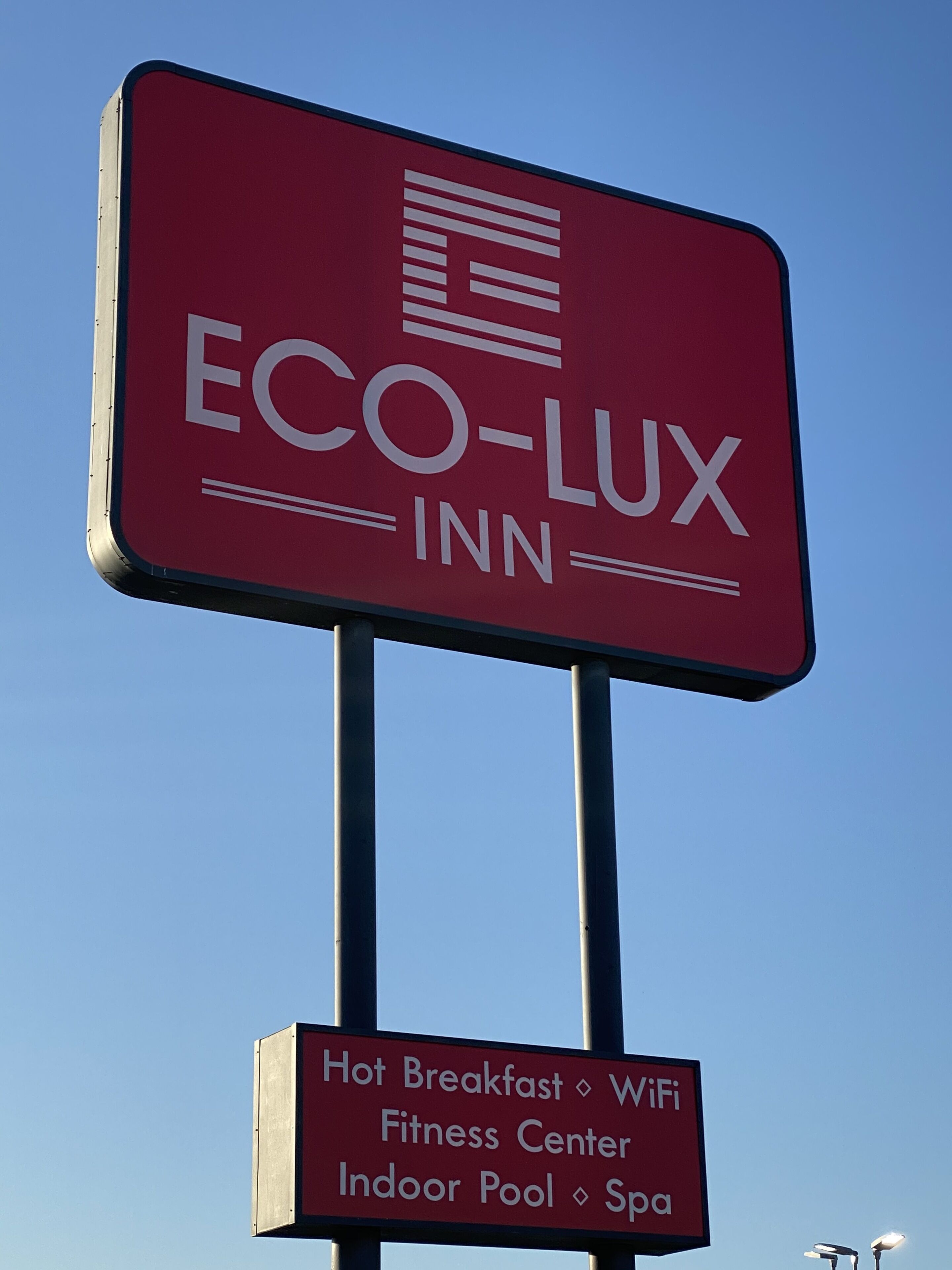 A sign for ECO-LUX INN highlighting amenities like hot breakfast, WiFi, fitness center, indoor pool, and spa.