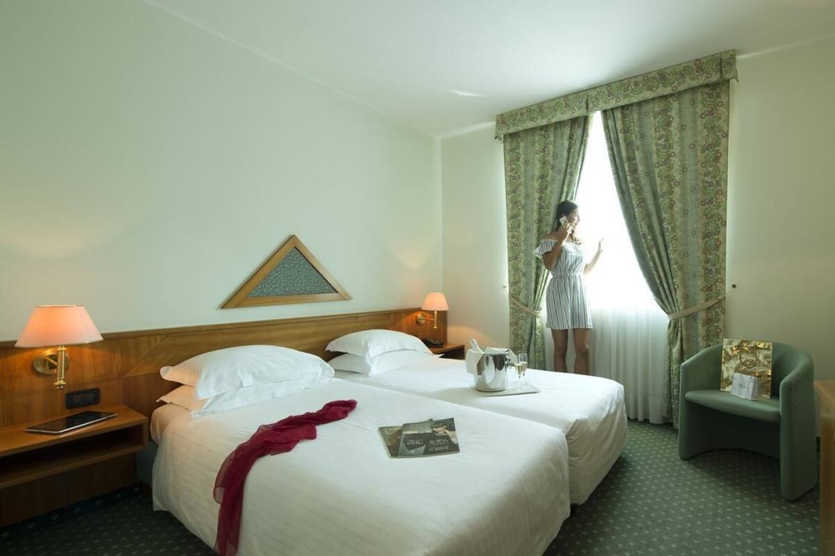 A hotel room with two beds, a television, a desk, and a chair.
