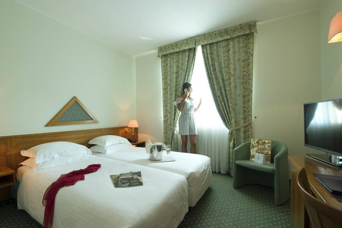 A hotel room with two beds, a television, a desk, and a chair.