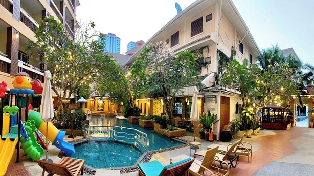 A hotel courtyard with a swimming pool, lounge chairs, and a children's play area. - Aiyaree Place Hotel (Pattaya)