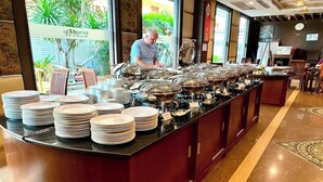A buffet setup with multiple serving stations, plates, and utensils. - Aiyaree Place Hotel (Pattaya)