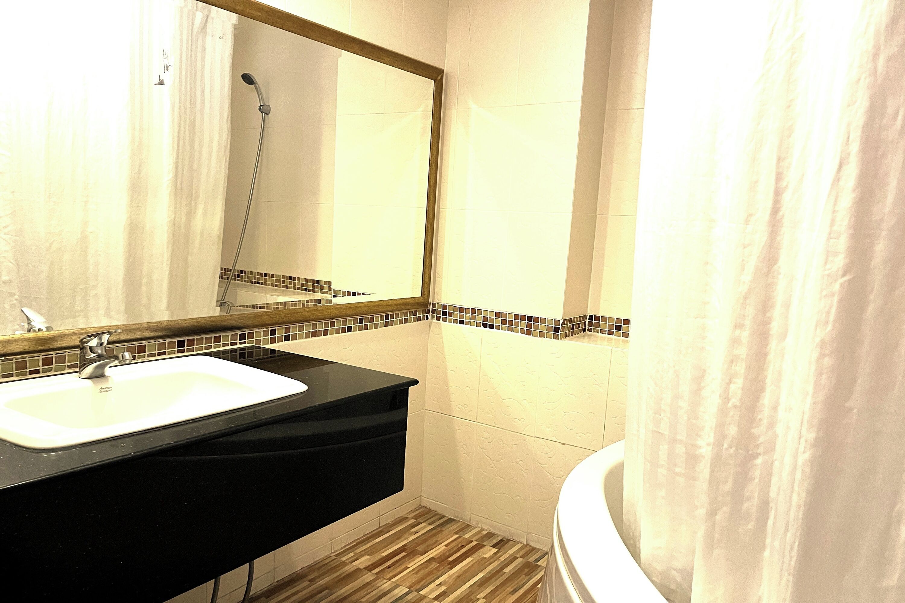 A bathroom with a white sink, black countertop, and a mirror above it.