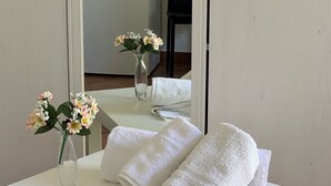 Una mesa blanca con dos toallas y un florero con flores.