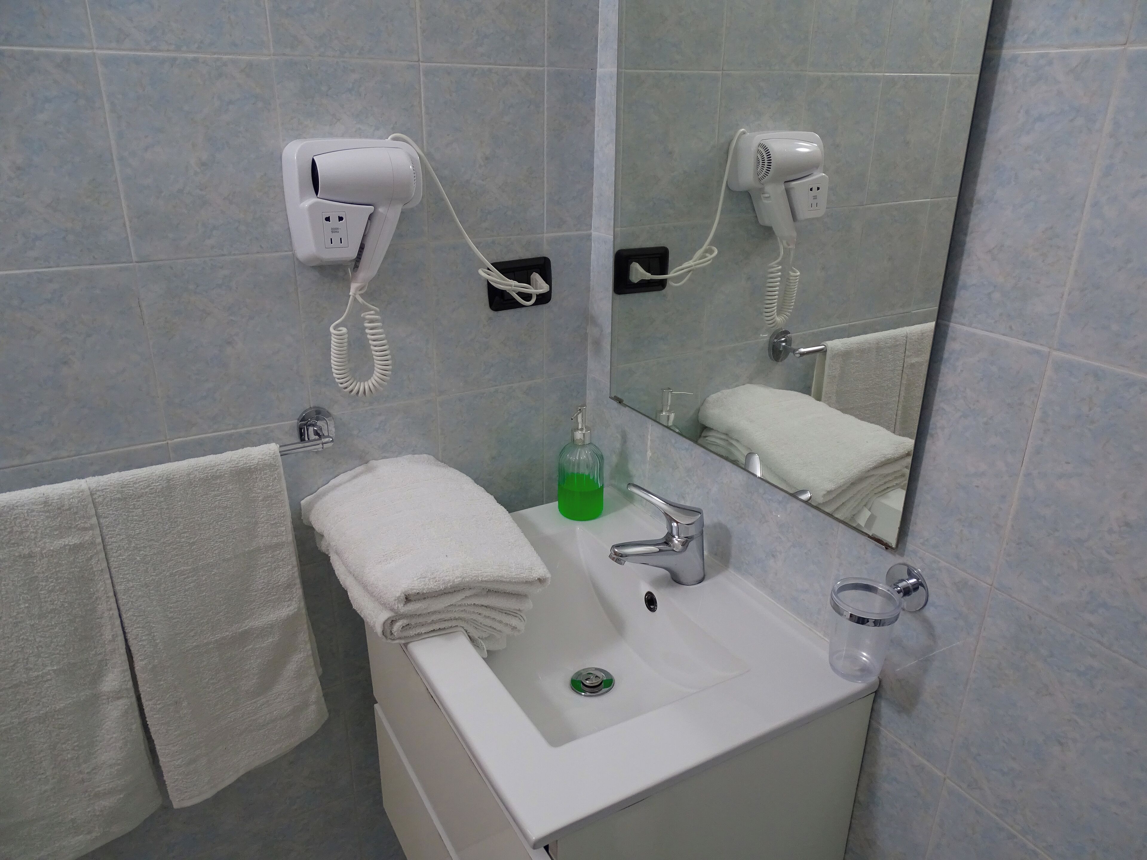 Bany amb un lavabo, mirall, paraigua i assecador.