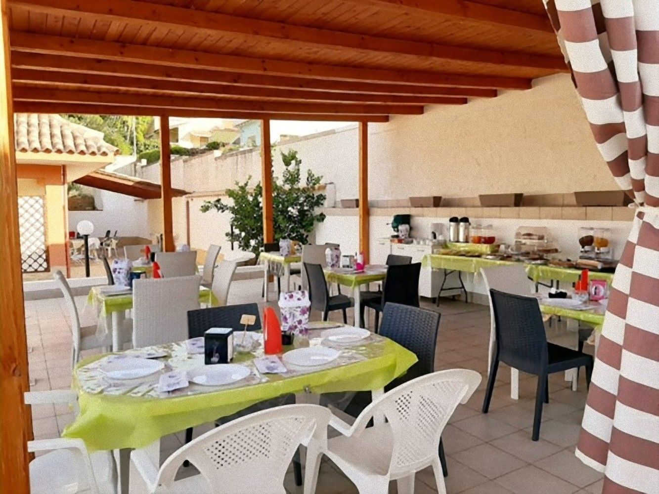 Een terras met tafels en stoelen, overdekt met een houten pergola.