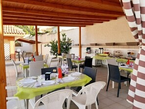 An outdoor dining area with tables and chairs, covered by a wooden pergola. - B&B Villa Matari (Syracuse)