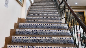 A staircase with blue and white patterned tiles, a black railing, and framed artwork on the walls. - Harmony Inn (Pattaya)