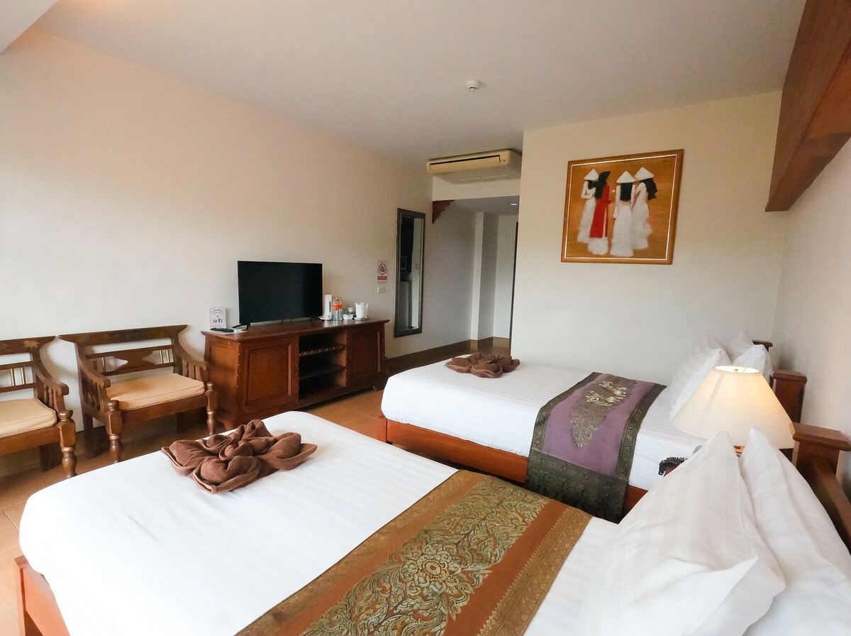 Habitación de hotel con dos camas, televisor, escritorio y un cuadro en la pared.