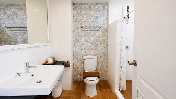 A bathroom with a white sink, a toilet, and a shower area.