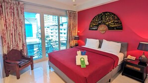 A hotel room with a bed, a nightstand, a chair, a large window, and a red wall. - Access inn Pattaya (Pattaya)