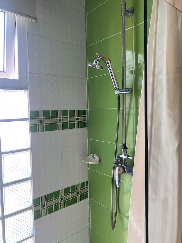A shower with a handheld showerhead and a wall-mounted faucet.
