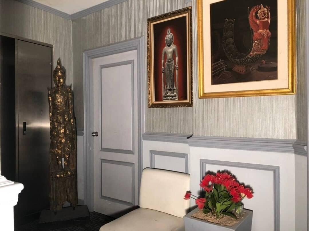 Ein Zimmer mit einer Statue, einem gerahmten Bild und einer Vase mit roten Blumen.