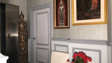 Ein Zimmer mit einer Statue, einem gerahmten Bild und einer Vase mit roten Blumen.