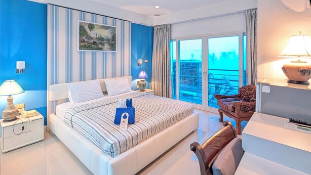 A modern hotel room with a large bed, a desk, a chair, and a view of the sea. - Access inn Pattaya (Pattaya)