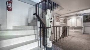 A staircase with a statue, a fire extinguisher, and framed artwork on the walls. - Access inn Pattaya (Pattaya)