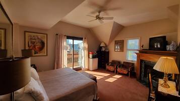 Une chambre à coucher avec un lit, un ventilateur de plafond, une cheminée et un balcon avec des rideaux.