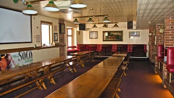 A restaurant with wooden tables and benches, brick walls, and hanging green lamps.