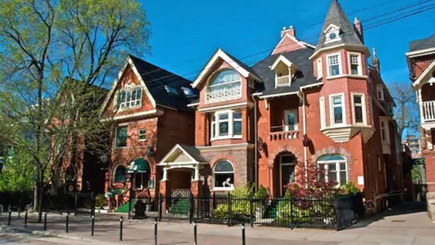 A Victorian-style building with multiple stories, large windows, and a prominent tower. - Madison Manor Boutique Hotel (Toronto)