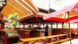 A rustic outdoor dining area with wooden benches and a red umbrella. - Madison Manor Boutique Hotel (Toronto)