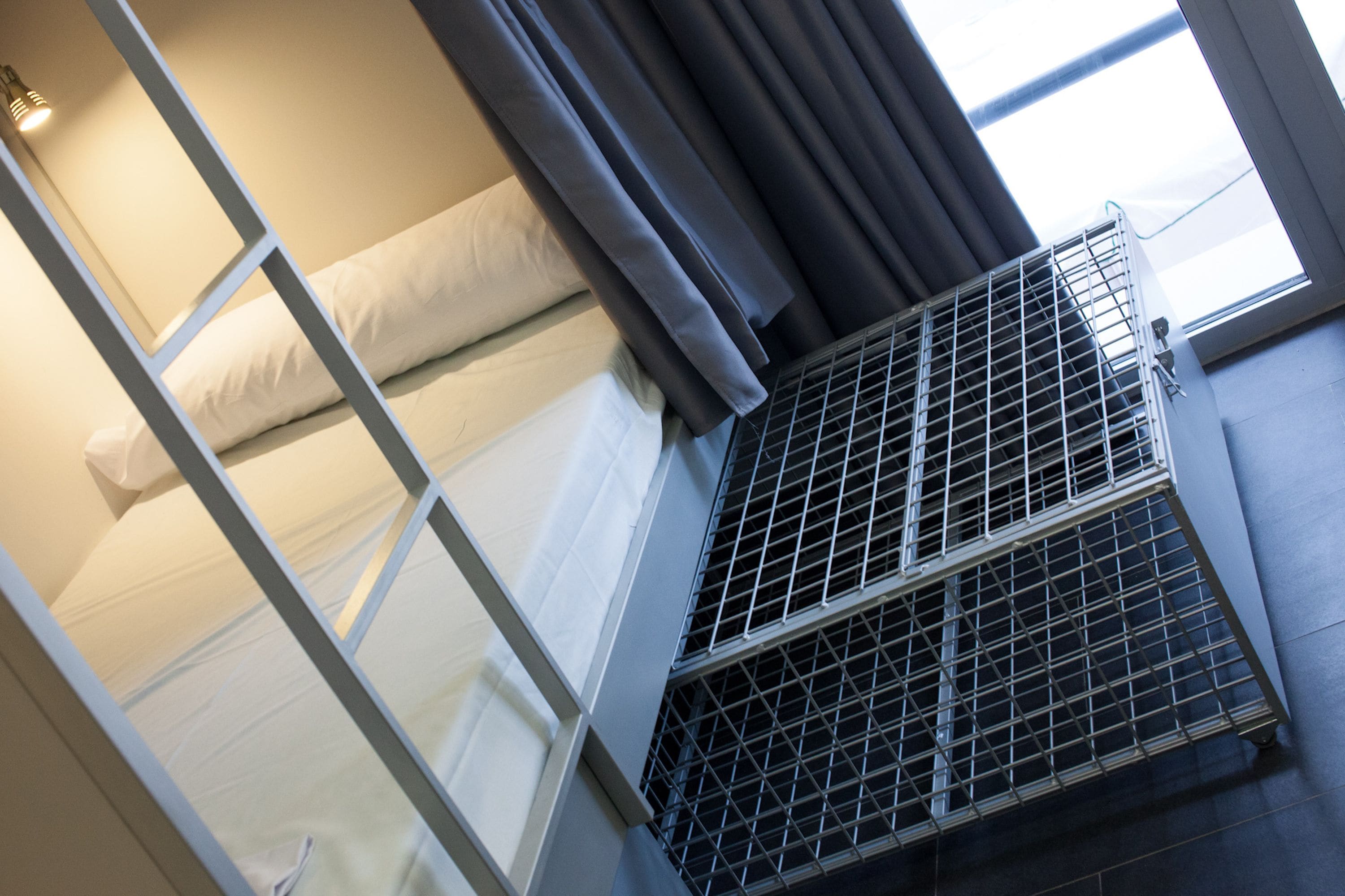 A bunk bed with white bedding and a metal air conditioning unit below it.