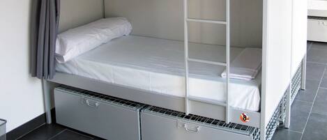 Una cama litera con escalera, un cajón pequeño y un estante.